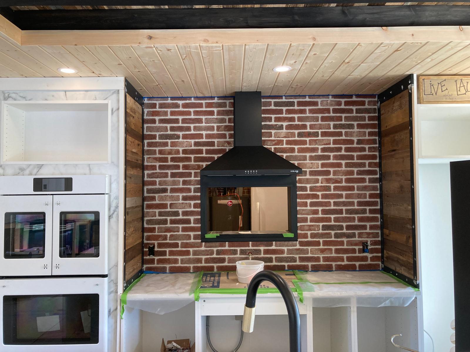 Kitchen cabinetry and brick feature wall during interior finishing