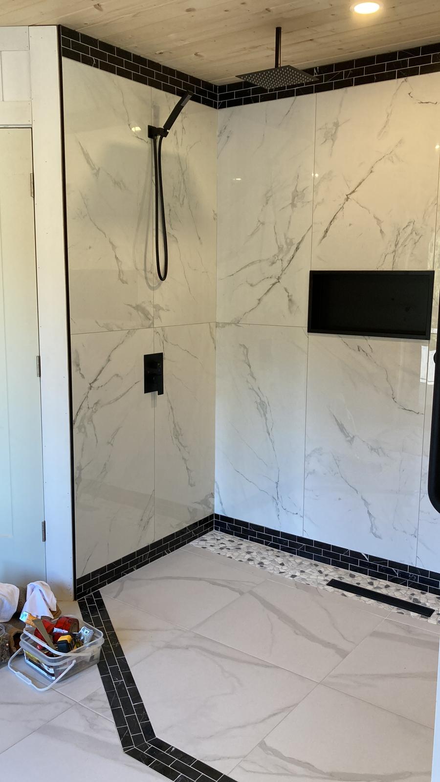 Custom tiled shower with black fixtures and a recessed niche